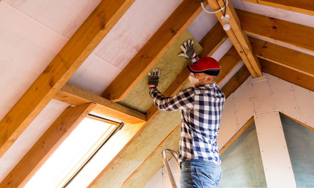 A man installing insulation in a home attic.