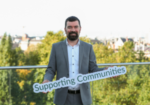 Joe O'Brien holds a sign reading 'Supporting Communities'