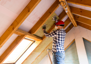 A man installing insulation in a home attic.