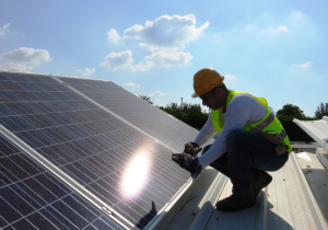 A man installs solar panels on a roof.