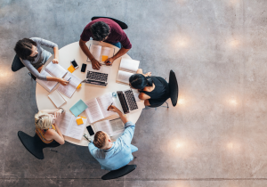 A group of people sit at a round table working on a project.