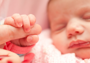 Newborn baby holds a parent's finger