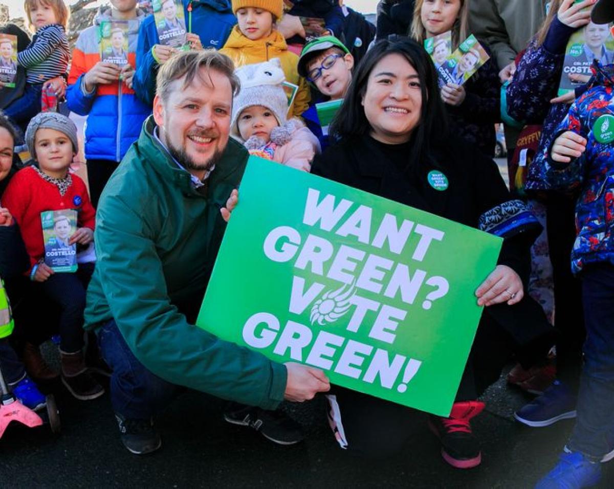 Photo of Patrick Costello and Hazel Chu holding a sign that reads 'Want Green? Vote Green!'